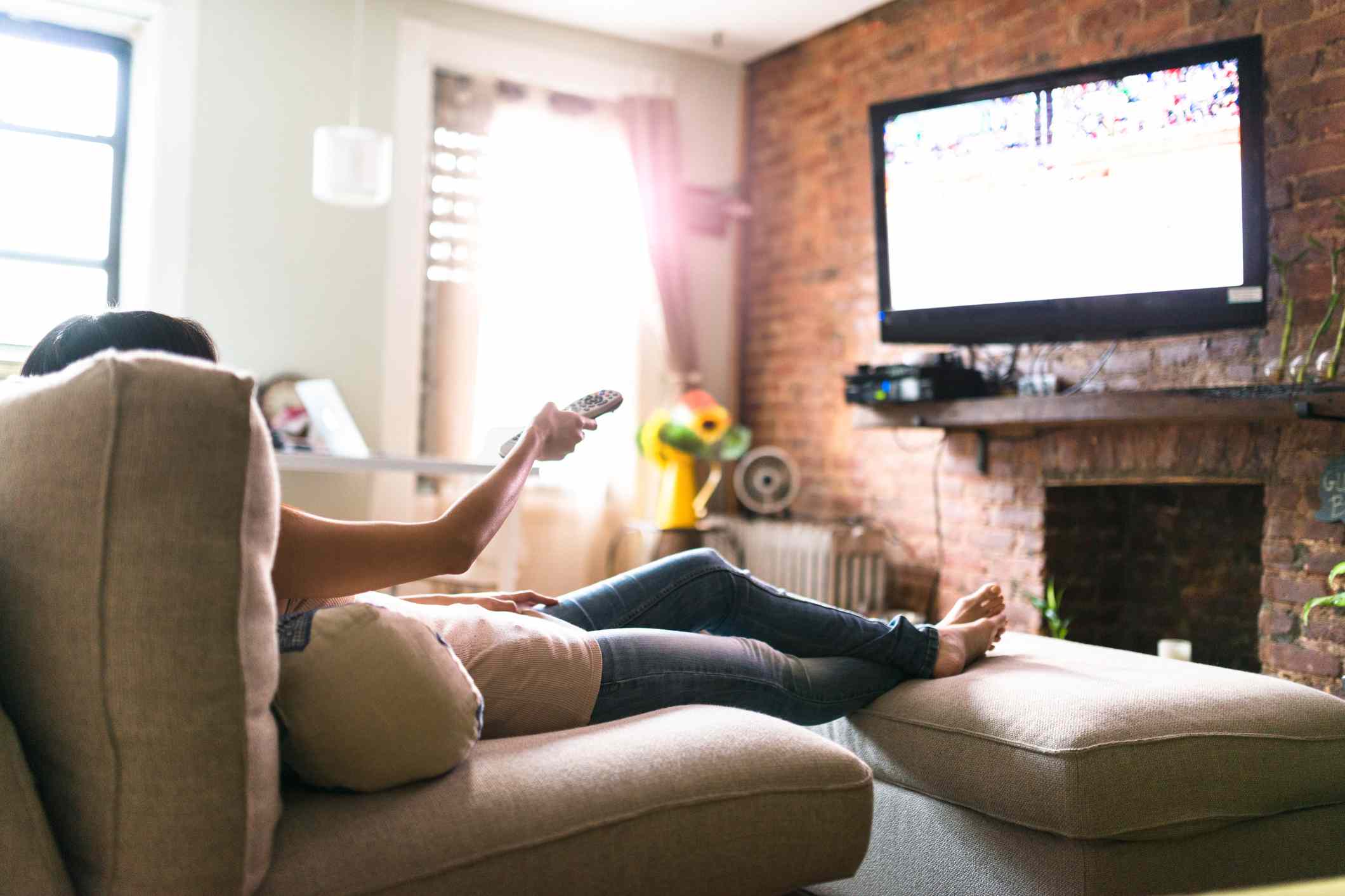 Watching TV while holding the remote and relaxing.