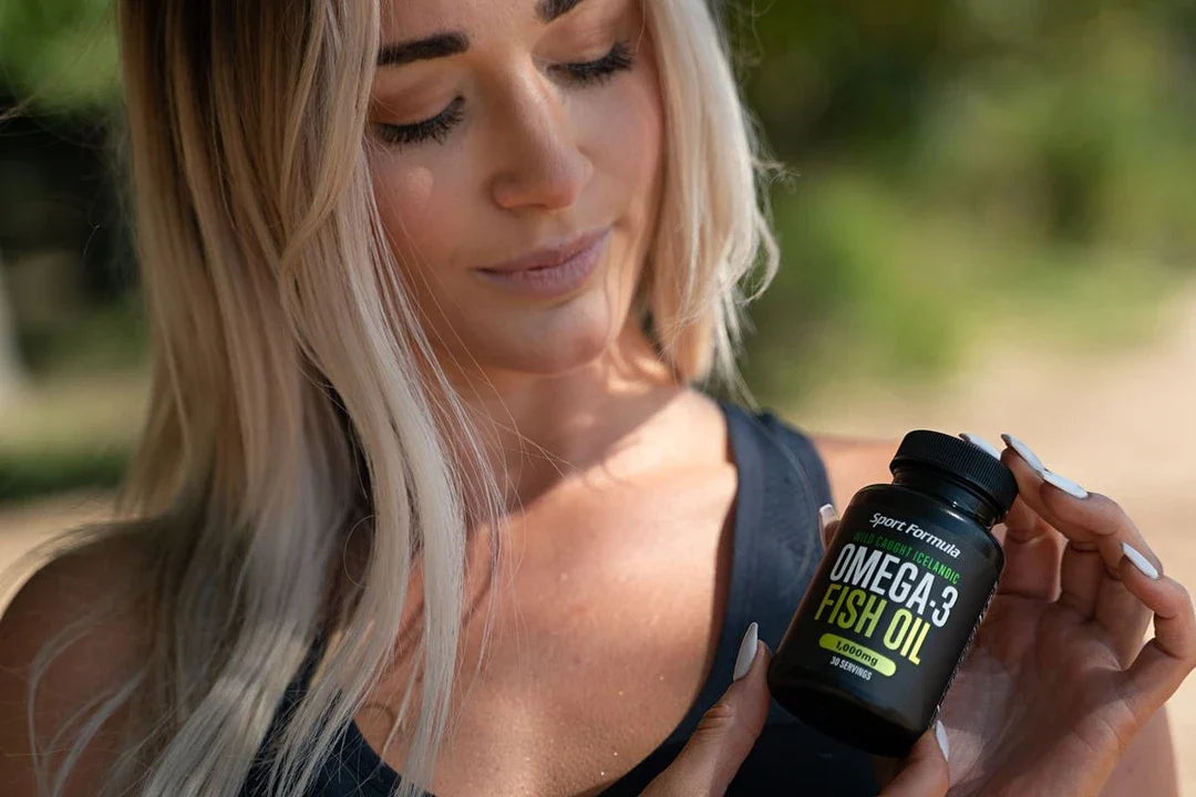 The woman is looking at the Omega fish oil while holding it.