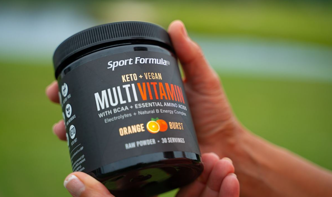 Holding a multivitamin tub with Orange Burst flavor.