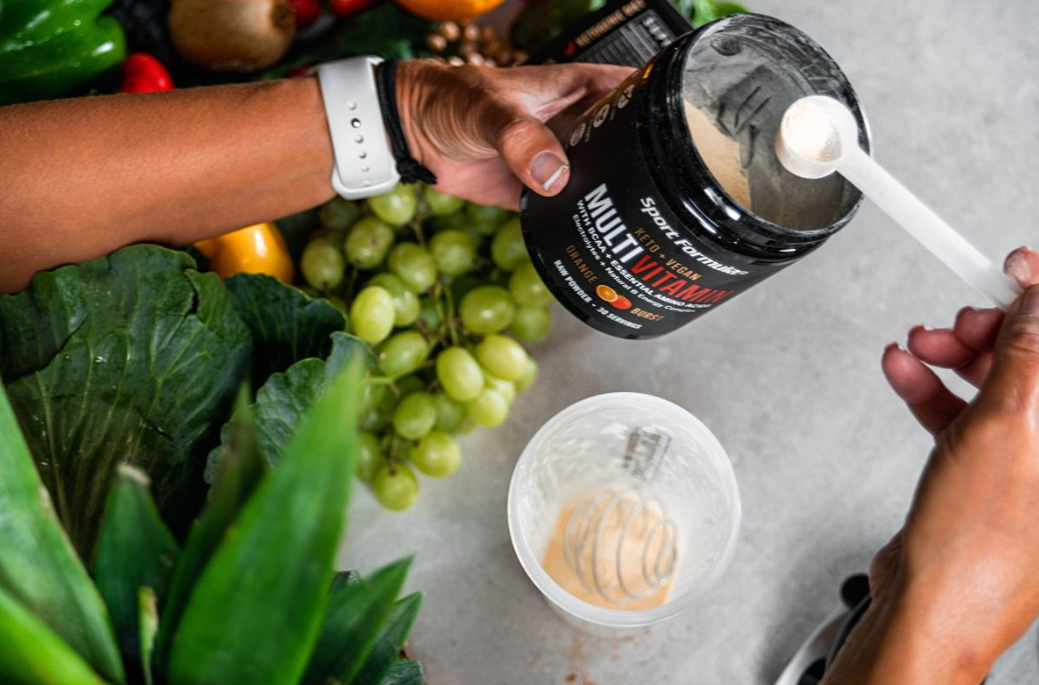 Showing the process of scooping from the Orange Burst multivitamin tub.