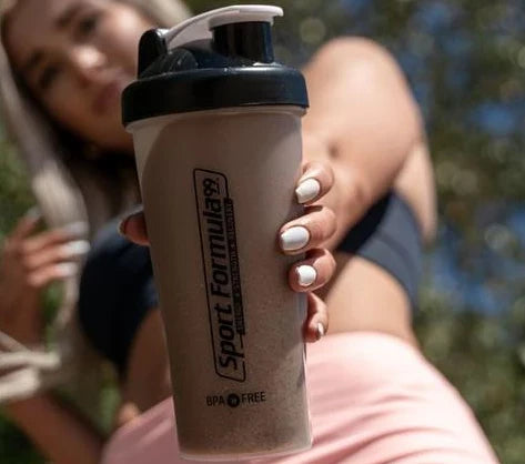 A shaker cup with mixed chickpea powder, with a woman holding it in the background.