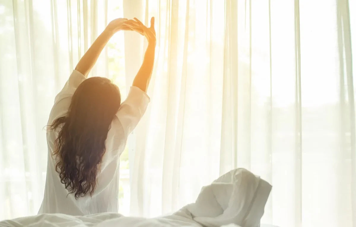 A woman stretching after just waking up in the morning.