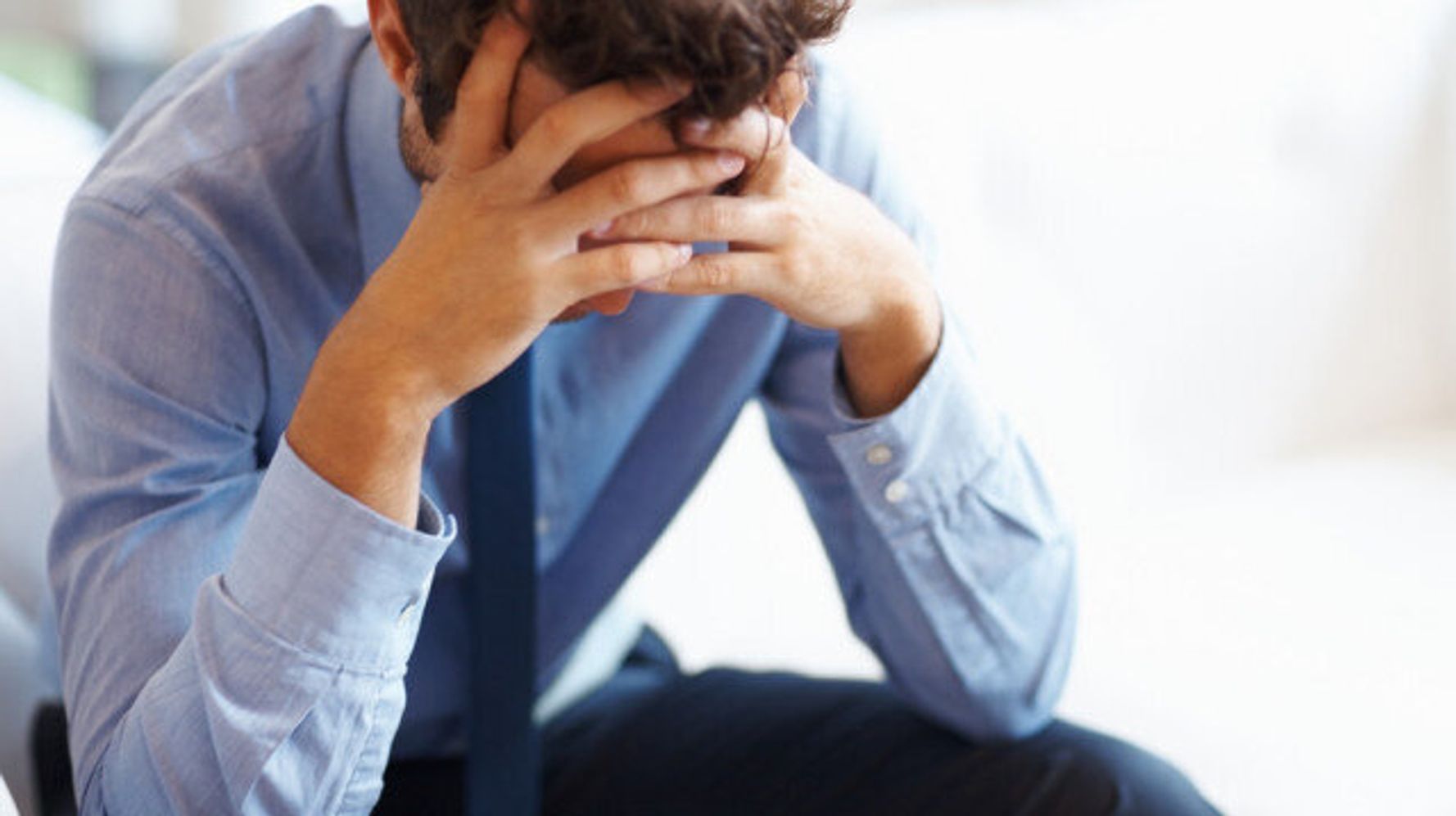 A man holding his head, visibly stressed and overwhelmed, with a tense expression, conveying the weight of mental strain and the emotional toll of stress.