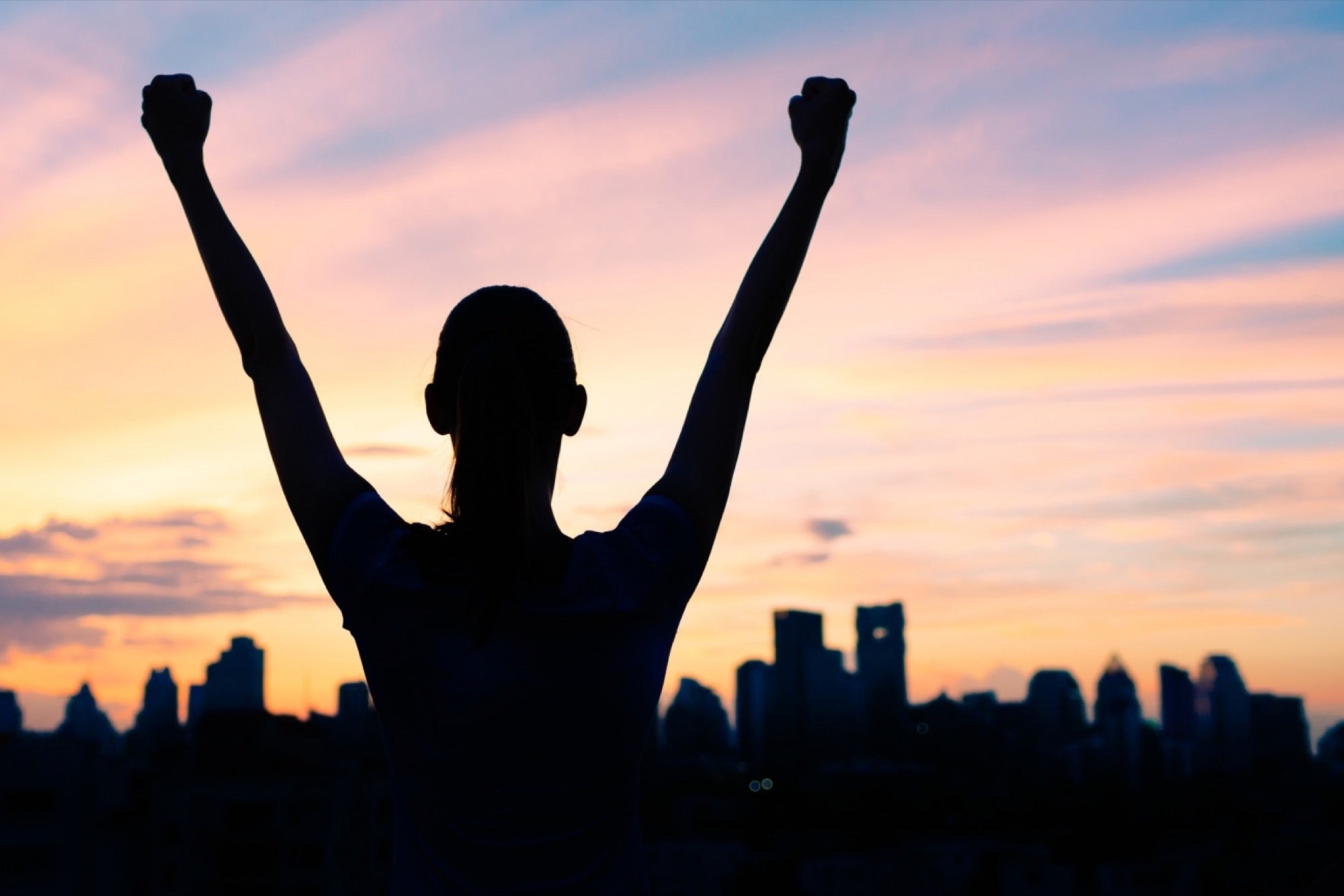 A woman with both arms raised, living in the moment.