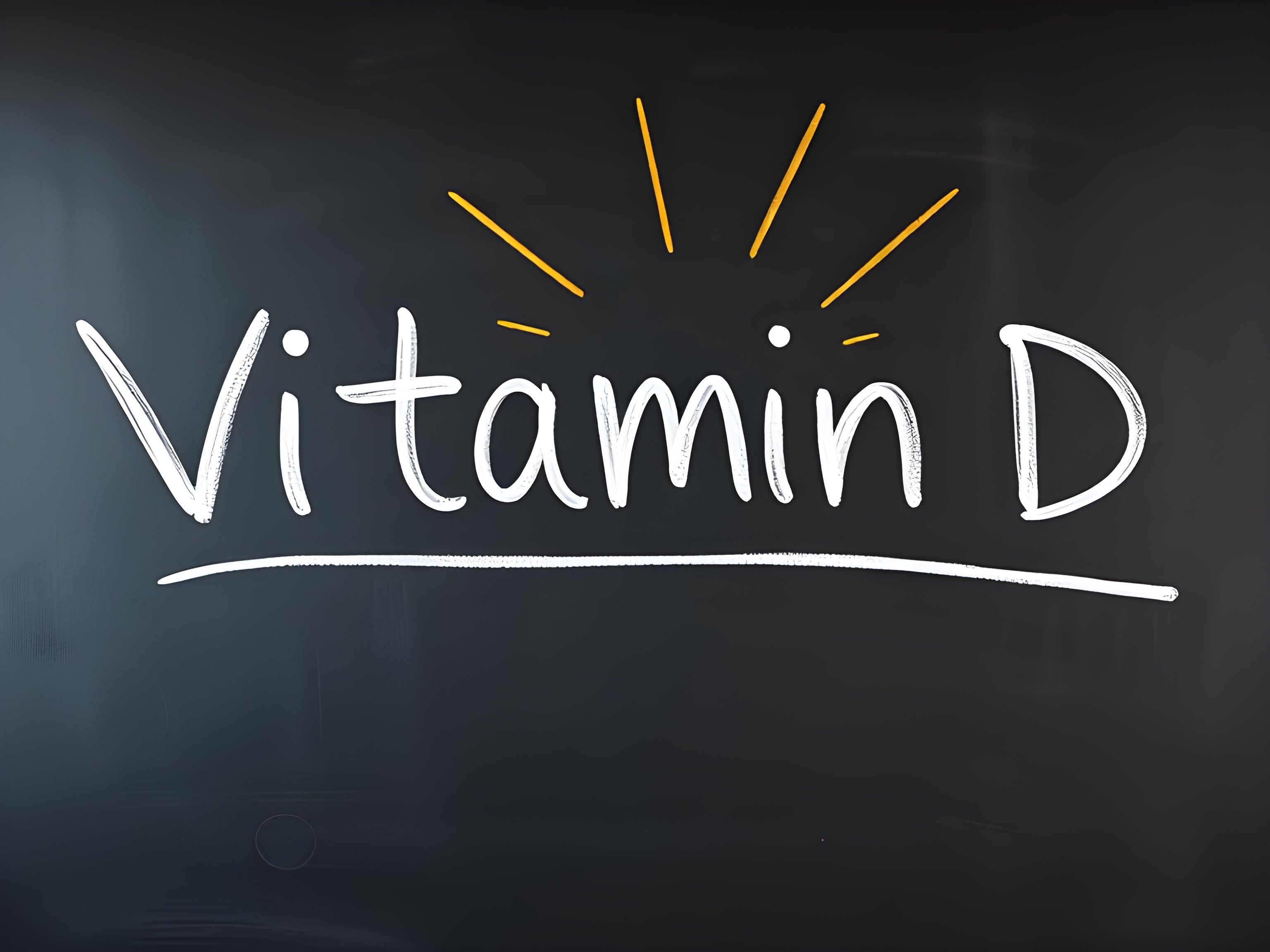 Chalkboard with handwritten text Vitamin D accented by rays, emphasizing its importance and vitality.