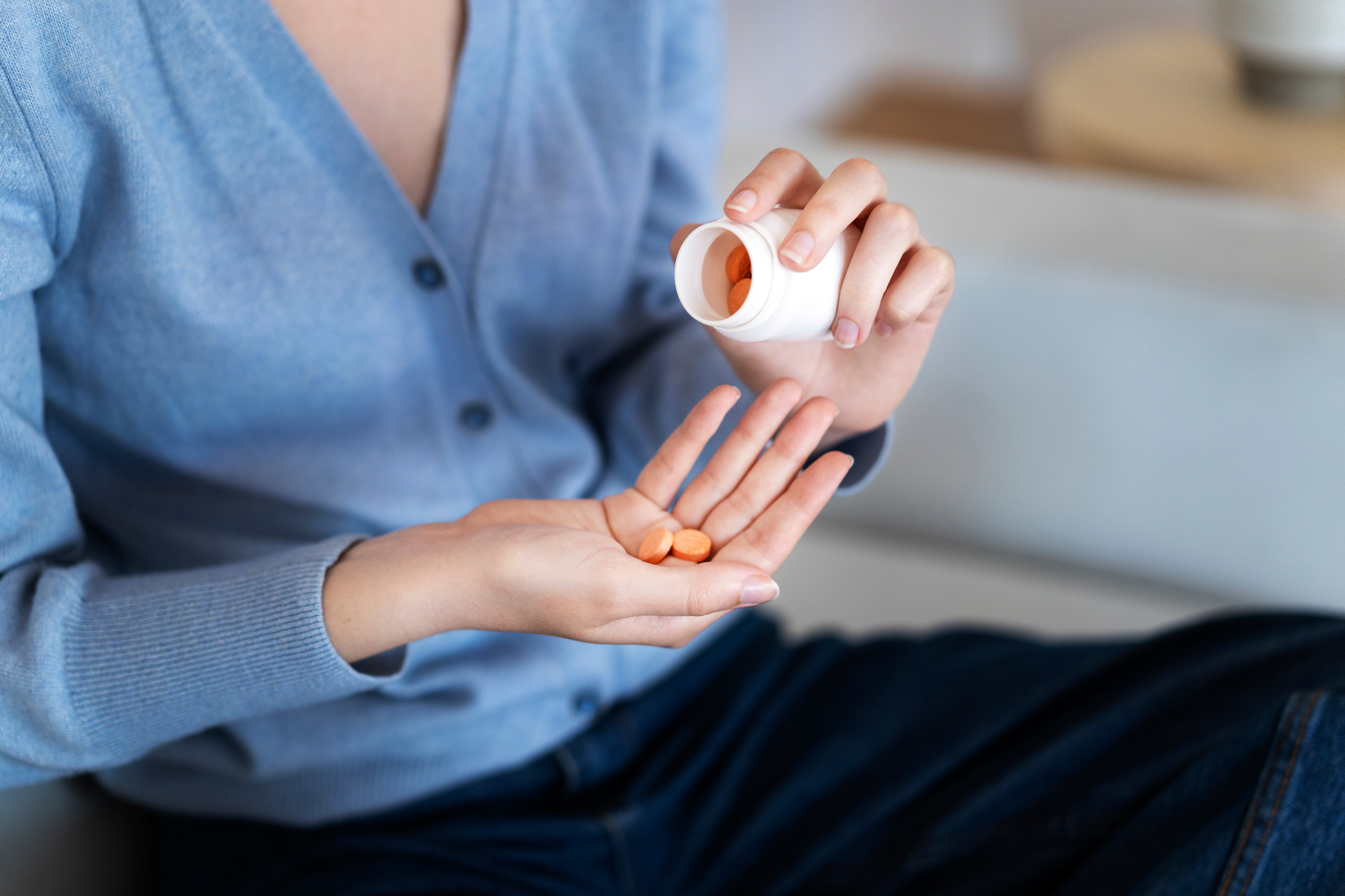 Person pouring pills from a bottle into hand.